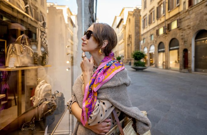 Woman looks on a showcase with bags on the street in old town